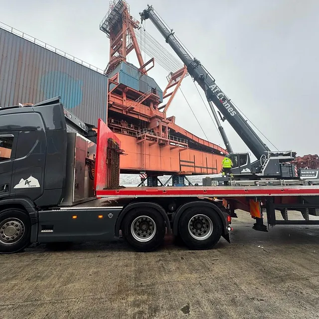 Lastebil og mobilkran fra AT Cranes arbeider ved kai med store lasteanlegg.